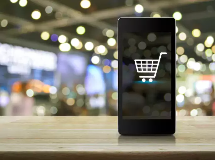 Shopping cart Icon on smart phone screen over blur mall